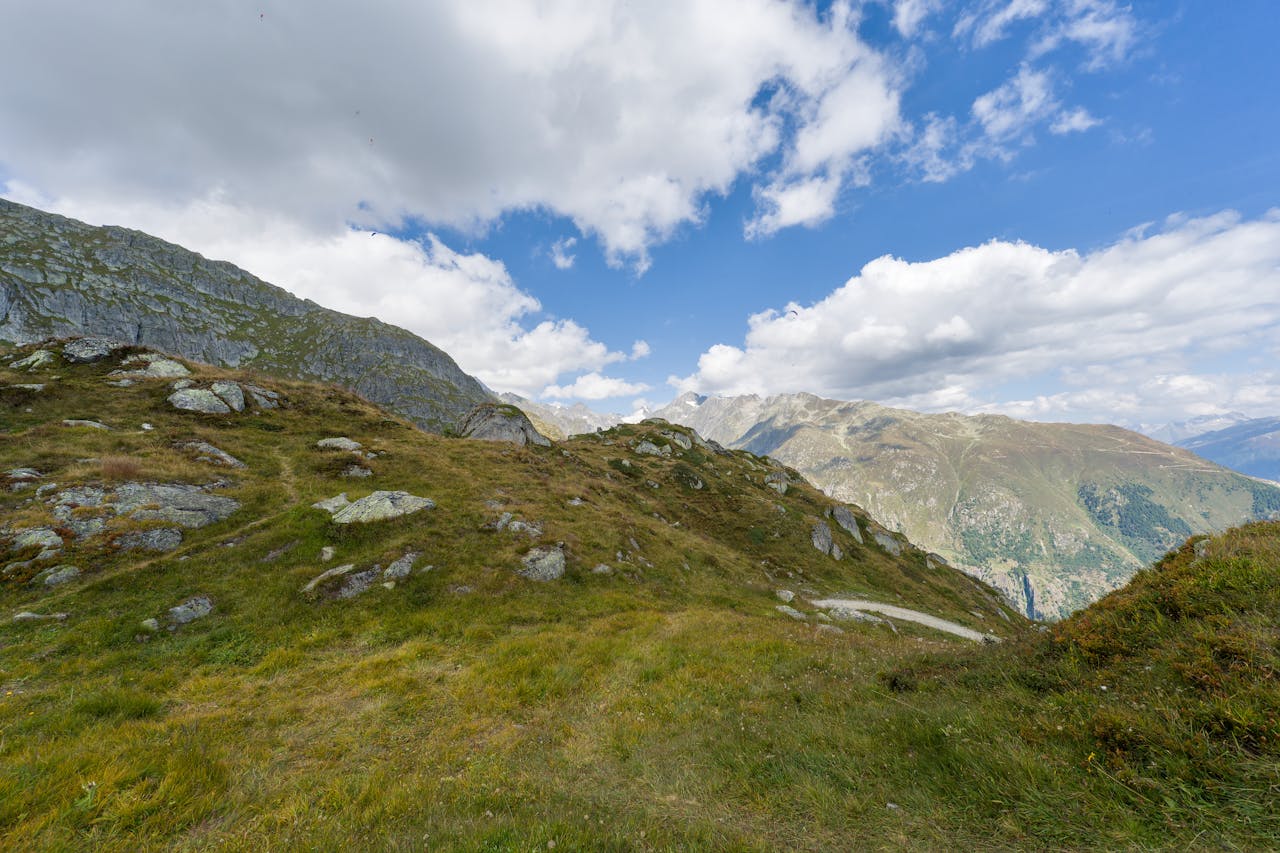 Breathtaking view of the Swiss Alps with lush green hills and a clear blue sky.